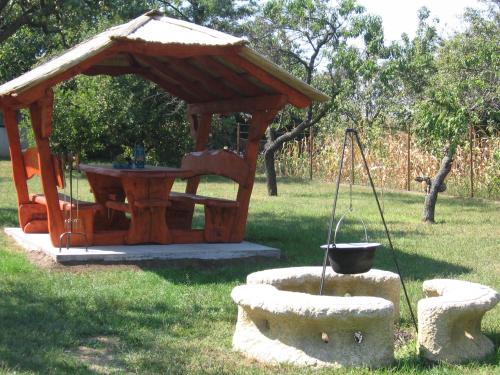 a wooden gazebo with a table and a swing at Manó Vendégház in Pázmánd