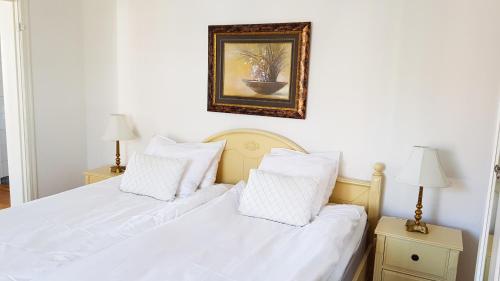 two beds with white sheets and a picture on the wall at Hotell Grönfeltsgården in Karlskoga