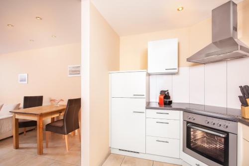 cocina con armarios blancos, mesa y fogones en AlpinAppartements Stöckl, en Partenen