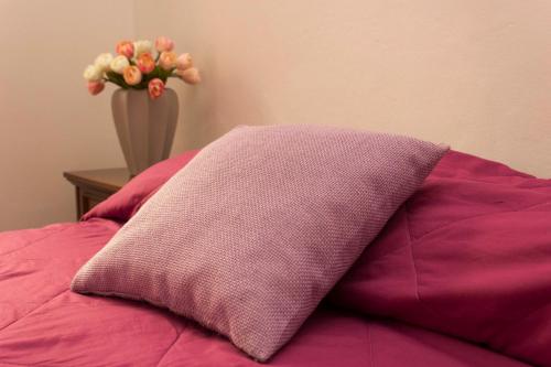 ein Kissen auf einem Bett mit einer Blumenvase in der Unterkunft CASA MADALI' - NEL BORGO in Marone