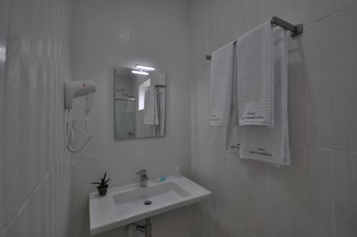 a white bathroom with a sink and a mirror at Porto Charming Hotel in Porto