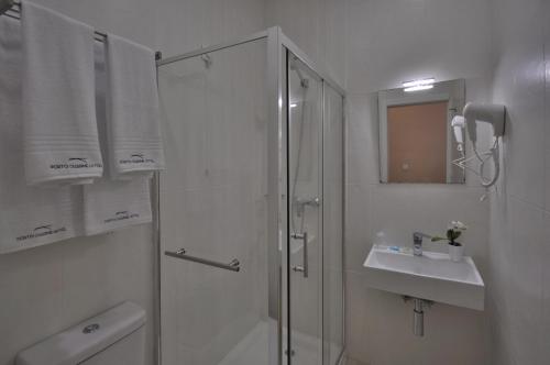 a white bathroom with a shower and a sink at Porto Charming Hotel in Porto