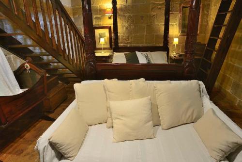a white couch with white pillows in a room at The Burrow Guest House in Tarxien