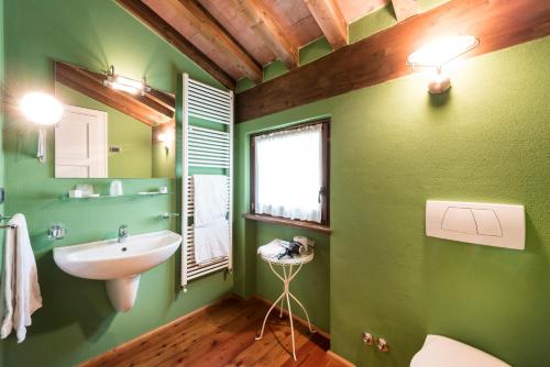 a bathroom with green walls and a sink and a window at Agriturismo Cà Del Lago in Gravedona