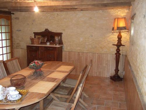a dining room with a wooden table and a lamp at La Ferme du Pech in Saint-Geniès