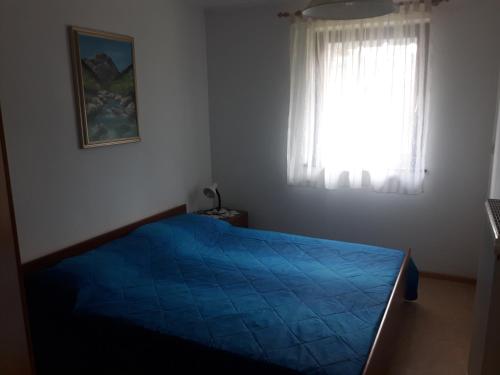 Un dormitorio con una cama azul y una ventana en Apartma Bel, en Žaga