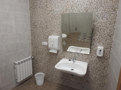 a bathroom with a sink and a mirror and a toilet at Albergue Buen Camino Tui in Tui