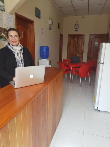 a woman sitting at a counter with a laptop at Hostal Marysol in Puerto Ayora