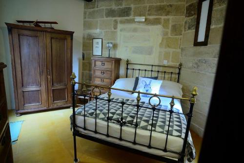 a bedroom with a bed and a wooden cabinet at The Burrow Guest House in Tarxien