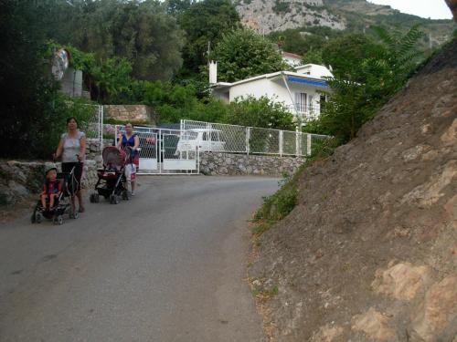 a group of people walking down a road with strollers at Apartmani CECA 012 Sutomore in Sutomore