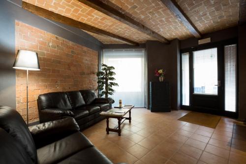a living room with black leather furniture and a brick wall at Camere Centro Storico in Canelli
