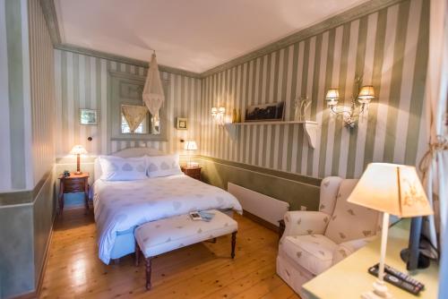 een slaapkamer met een bed, een stoel en een bank bij Anerada inn Suites & Villa - Pet Friendly in Karpenisi
