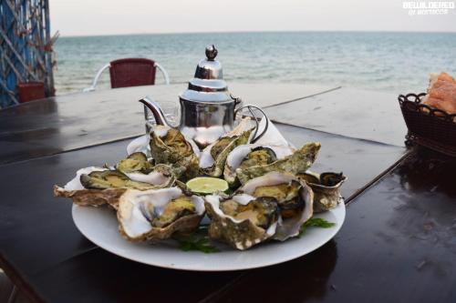 ein Teller Austern auf einem Tisch neben dem Meer in der Unterkunft Résidence Tamaya in Ad-Dakhla