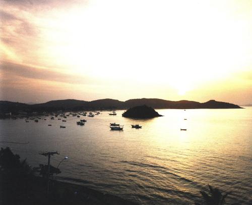 a group of boats in the water at sunset at Pousada Dos Búzios in Búzios