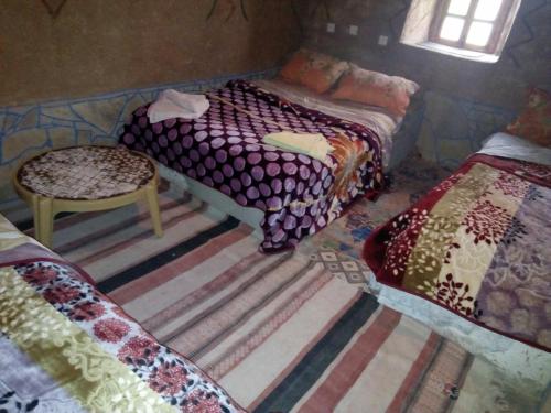 a bedroom with two beds and a table and a chair at Auberge Amazigh in Tamtetoucht