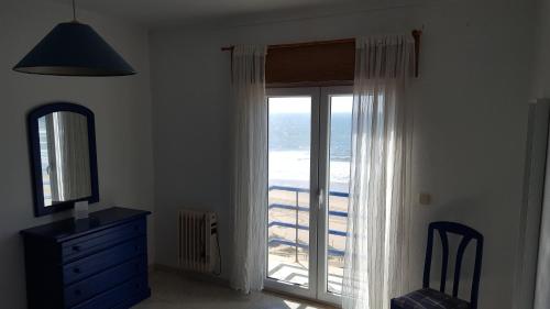 a bedroom with a sliding glass door with a view of the ocean at Hotel Apartamento Praia Azul in Santa Cruz