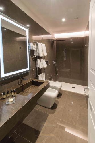 a bathroom with a toilet and a sink and a mirror at Caruso Place Boutique & Wellness Suites in Naples