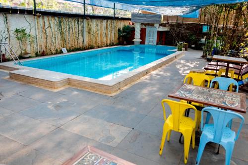 a swimming pool with tables and chairs next to it at Casa Menezes - A Heritage Goan Homestay in Bambolim