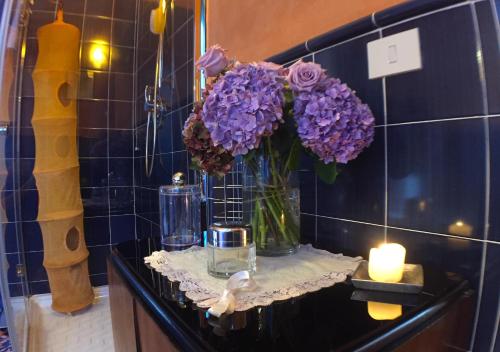 a vase of purple flowers and a candle on a counter at Villa Pieve De' Pitti in Terricciola