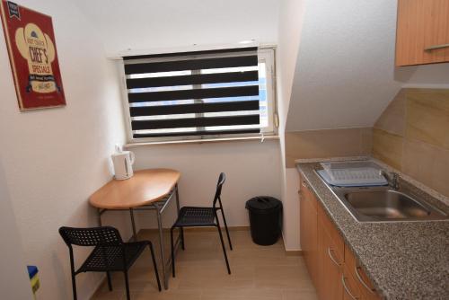 une petite cuisine avec une table, des chaises et un évier dans l'établissement Apartment Hedelfingen I, à Stuttgart