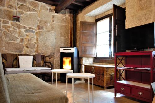 a room with a fireplace and a bed and chairs at A Lareira De Allariz in Allariz