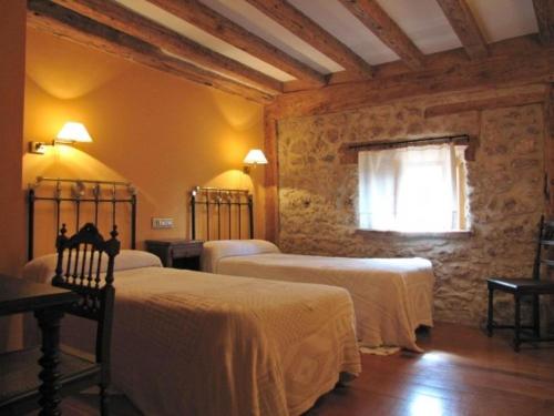 カラタニャソルにあるCasa Rural de la Villaのベッドルーム1室(白いシーツが備わるベッド2台、窓付)