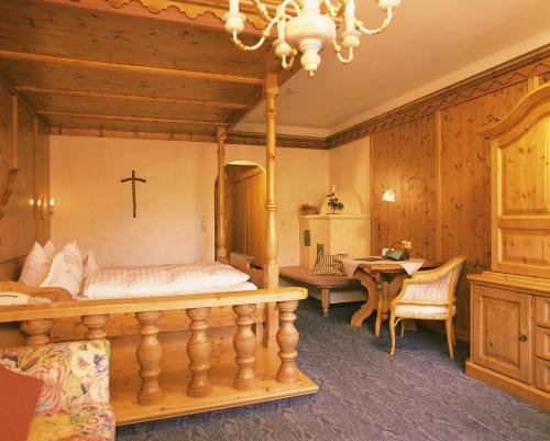 a bedroom with a large bed and a table at Das Traditionshotel Schwarzer Adler in Tannheim