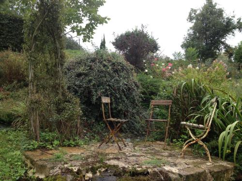 two old chairs sitting in the middle of a garden at au balcon du bonheur in Malandry