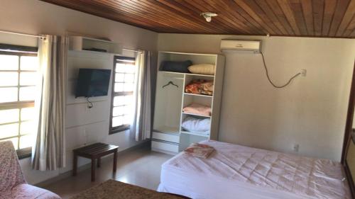 um quarto com uma cama e uma televisão num quarto em Baleia Branca Chalé em Porto Belo