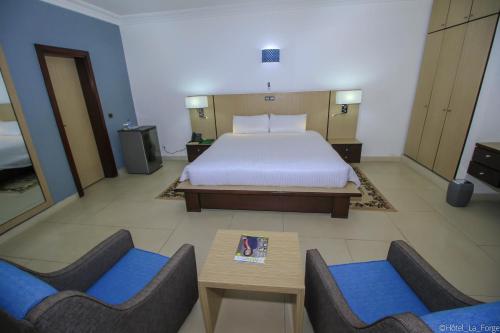 une chambre d'hôtel avec un lit et deux chaises dans l'établissement Hotel LAFORGE, à Abidjan