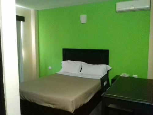 a green room with a bed and a green wall at CHN Hotel Monterrey Santa Fe in Monterrey