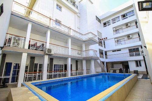 an apartment building with a swimming pool in front of it at Hotel LAFORGE in Abidjan