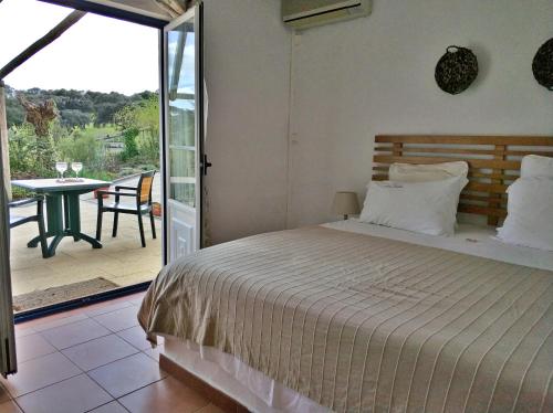 a bedroom with a bed and a balcony with a table at Hotel Rural da Ameira in Montemor-o-Novo