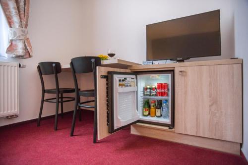 a small refrigerator with two chairs and a tv on top at Penzion Obora in Poděbrady
