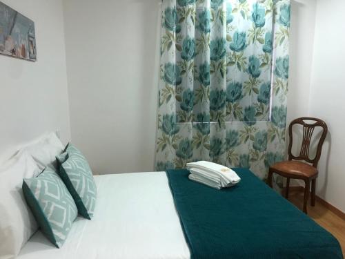 a bedroom with a bed with a green blanket and a chair at Soldouro Guesthouse in Aveiro