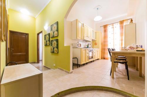 una cucina con pareti gialle, tavolo e sedie di Albachiara Guest House a Roma