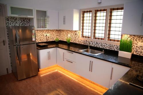 a kitchen with white cabinets and a stainless steel refrigerator at Luxury Villas of Guruvayur in Guruvāyūr