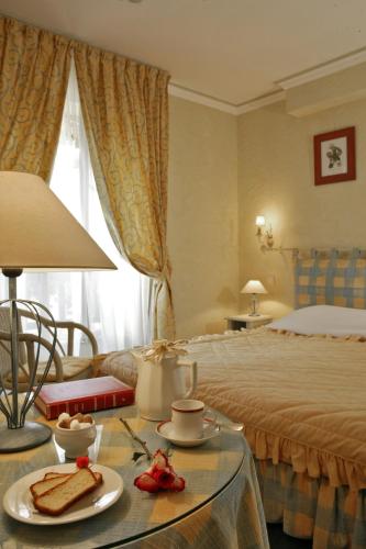 a hotel room with a bed and a table with food on it at Hostellerie du Passeur - Hôtel & Restaurant - Climatisation et Piscine chauffée in Les Eyzies-de-Tayac