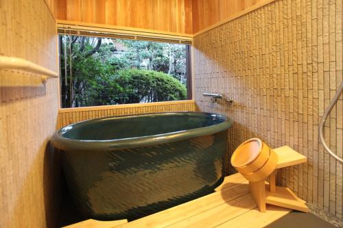 uma casa de banho com uma grande banheira verde e uma janela em Ryori Ryokan Tsurugata em Kurashiki