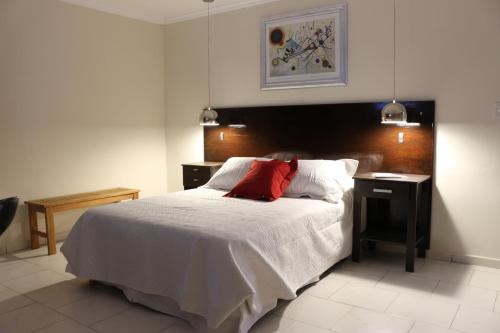a bedroom with a bed with a red pillow on it at Eclat Suites Hotel Boutique in Villa Mercedes