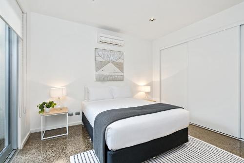 a white bedroom with a bed and a window at Cogens Two Bedroom Townhouse in Geelong