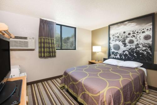 a small hotel room with a bed and a window at Super 8 by Wyndham Jamestown in Jamestown