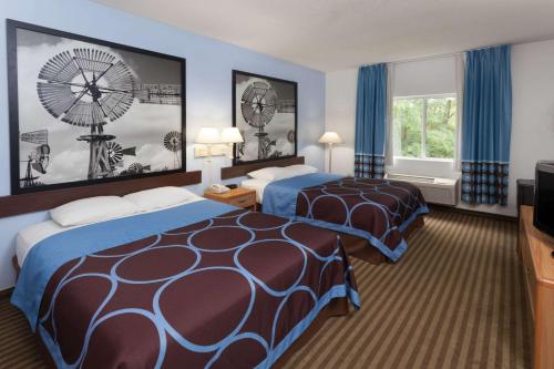 a hotel room with two beds and a windmill on the wall at Super 8 by Wyndham Huntington in Huntington