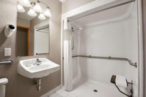 a white bathroom with a sink and a shower at Super 8 by Wyndham Green Bay I-43 Bus. Park in Green Bay