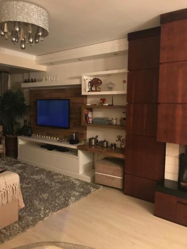 a living room with a flat screen tv and a couch at Lindo apartamento no centro de Canela in Canela
