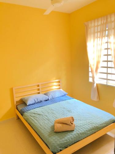 a yellow bedroom with a bed with a towel on it at Twin Homestay C in Kuala Terengganu