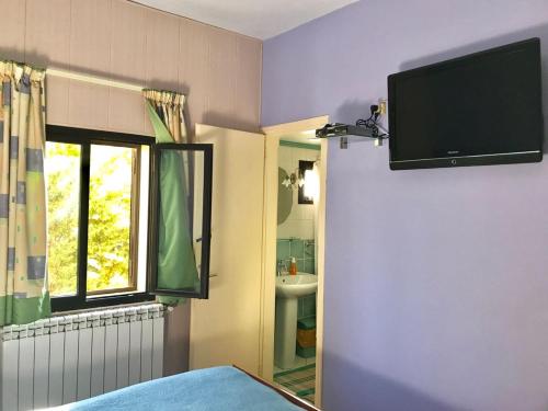 a bedroom with a tv on the wall and a window at Stone Chalets in Fārayyā