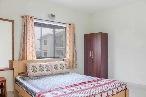 a small bedroom with a bed and a window at Sun & Sand in Candolim