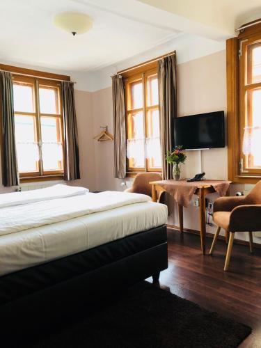 a bedroom with a bed and a desk and a television at Zum Fehmelbauer in Karlstadt