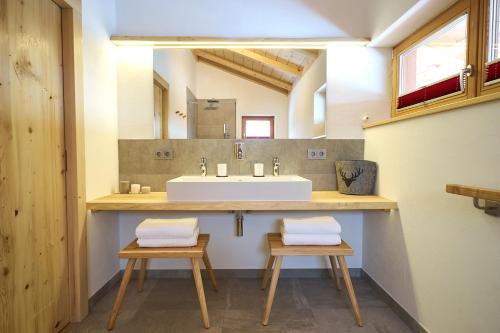 Un baño con lavabo y dos taburetes debajo. en Ferienhaus In den Bergen, en Oberammergau